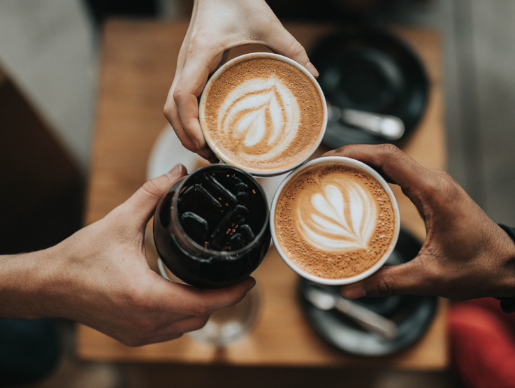 three hands holding different cups of coffee
