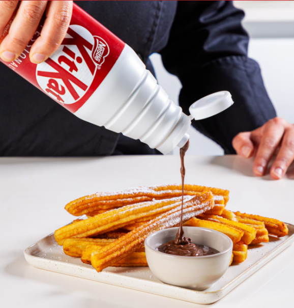 pouring kitkat sauce on churros